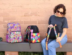Frau trägt Rucksack mit Regenbogen-FPP-Trägern und hält passende Tasche im gleichen Design.