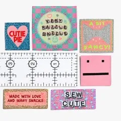 Labels aus dem Wearable-Art-Set: „Cutie Pie", „Very Razzle Dazzle", „A Bit Fancy!", ein pinkes Smiley-Gesicht, „Made With Love And Many Snacks" und „Sew Cute".