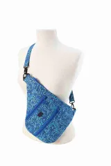 Am Modell getragene Tasche in blau-türkisem Paisley-Batikmuster mit Cross-Body-Riemen.