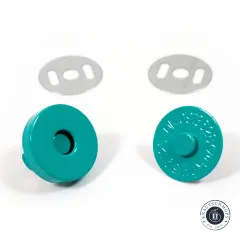 Detailaufnahme der beiden türkisfarbenen Snap-Hälften – links die Buchse mit runder Vertiefung, rechts der Kopf mit Prägeschrift –, darüber jeweils die passende Unterlegscheibe.