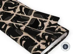 Zusammengelegter Canvasballen zeigt den Faltenwurf des Grumpy-Whale-Designs in Schwarz auf Naturbeige.