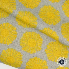 Diagonal gefaltete Canvasecke zeigt Musterverlauf der senfgelben Sonnenmotive auf Graubeige.