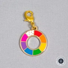 Zipper Charm „Color Wheel" freigestellt auf hellgrauem Stoff, von oben fotografiert.