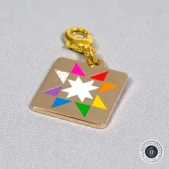 Zipper Charm „Quilt Star" freigestellt auf hellgrauem Stoff, von oben fotografiert.