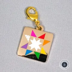 Zipper Charm „Quilt Star" in Nahaufnahme, schräg auf Stoff liegend.