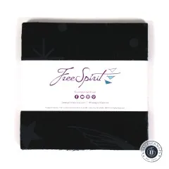 Der gestapelte Charm Pack von oben mit mittiger FreeSpirit-Banderole auf dem schwarzen Sternschnuppen-Stoff.