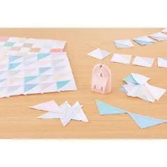 Übersicht eines Patchwork-Arbeitsplatzes mit fertigen Blöcken, Dreieck-Zuschnitten und dem Clover „Quick Cut" Fadenschneider.