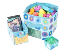Stoffkörbe in blauem Kreismuster "Liam's Toys" mit Bauklötzen und "DVDs" mit Filmen befüllt.