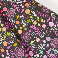 Nahaufnahme des gefalteten Stoffs mit Pusteblumen und Farnzweigen in Pink/Lila auf schwarzem Grund