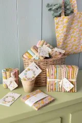 Deko-Ansicht: Weidenkorb mit gerollten Stoffen der Spring-Kollektion und Tragetasche aus passendem Blumenstoff.