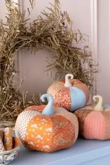 Drei genähte Stoffkürbisse aus der Autumn-Kollektion vor einem herbstlichen Kranz.