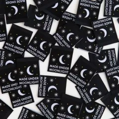 Dicht gestreute schwarze Sarah-Hearts-Weblabels „Made Under Moonlight" mit Mond- und Sternmotiv in verschiedenen Ausrichtungen.