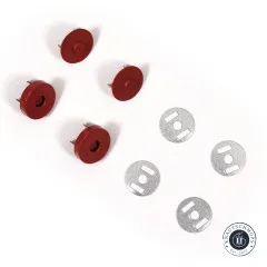 Ein ziegelroter Druckknopf von vorne mit Loch und von hinten mit Noppe, im unscharfen Hintergrund zwei Unterlegscheiben.
