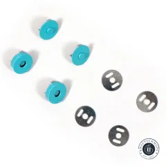 Ein türkisblauer Druckknopf von vorne mit Loch und von hinten mit Noppe, im unscharfen Hintergrund zwei Unterlegscheiben.