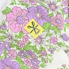 Label „Fabric Only Mother Fuckers" mit Scheren-Motiv eingenäht in lila-rosa geblümten Stoff.