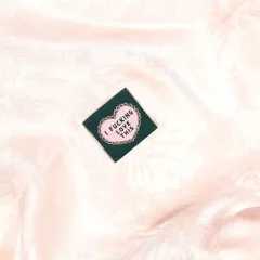 Herzlabel „I fucking love this" eingenäht in rosafarbenen Jacquard-Satin mit Blütenmuster.