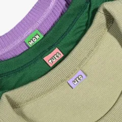 Die Label „Mon", „Tues" und „Wed" eingenäht in die Kragen dreier verschiedenfarbiger Nähprojekte.