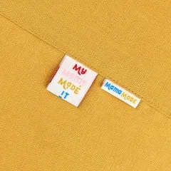 Die Labels „My Mama Made It" und „Mama Made" eingenäht in ein senffarbenes Nähprojekt.