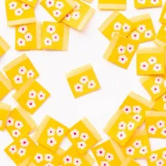 Ein gelbes Weblabel mit drei weißen Gänseblümchen mittig platziert, umgeben von locker verstreuten weiteren Labels.