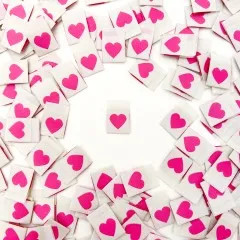 Ein cremefarbenes Weblabel mit pinkfarbenem Herz mittig platziert, umgeben von locker verstreuten weiteren Labels.