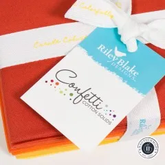 Nahaufnahme des Etiketts Confetti Cotton Solids auf dem orangefarbenen Stoffbündel