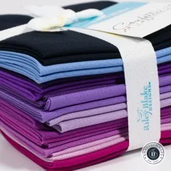 Nahaufnahme des Etiketts Confetti Cotton Solids auf dem violetten Stoffbündel