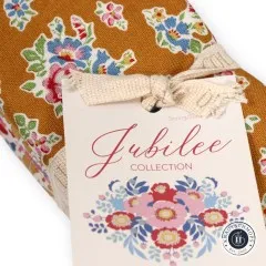 Nahaufnahme des Jubilee-Collection-Etiketts auf dem mustardfarbenen Blumenstoff