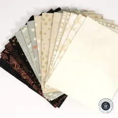 Aufgefächerte Ansicht der hellen Stoffe mit Gold-Metallic-Akzenten in Beige, Grau und Schwarz