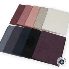 Alle 10 Fat Quarters fächerförmig ausgelegt, warme Mauve- und Rosatöne oben, kühle Blau- und Schwarztöne unten.