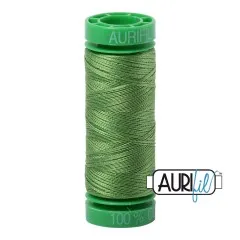 Aurifil-Garnrolle mit grünen Endkappen und kräftig grasgrünem Baumwollgarn.