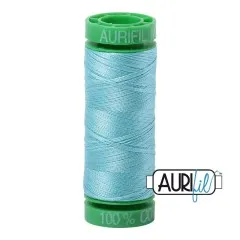 Aurifil-Garnrolle mit grünen Endkappen und hellem, türkisblauem Baumwollgarn.