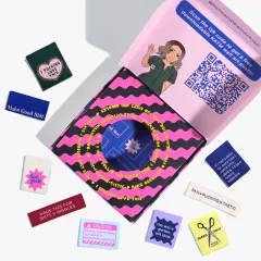 Geöffnete Box mit Illustration und QR-Code im Deckel, umringt von den neun losen Labels des Sets.