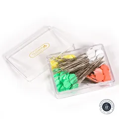 Geöffnete Aufbewahrungsbox mit den Stecknadeln in den Farben Gelb, Grün, Weiß und Orange.