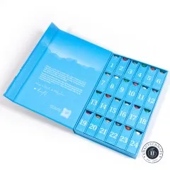 Geöffnete Adventskalender-Box mit 24 nummerierten Fächern, in denen bunte Garnspulen sichtbar sind, und Grußtext von Aurifil im Deckel.