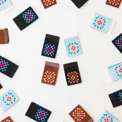 Sarah Hearts Weblabels „Granny Squares" in vier Farbvarianten locker verteilt auf weißem Untergrund