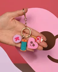 Gratis Schlüsselanhänger mit Garnrolle, Herz und Label-Charms in einer Hand