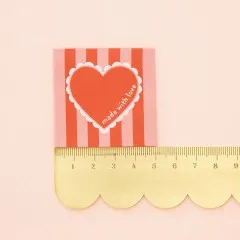 „Made with Love“-Label neben einem goldenen Lineal zum Größenvergleich.