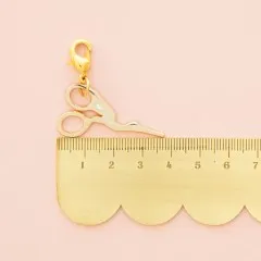 Zipper Charm neben einem goldenen Lineal zum Größenvergleich.