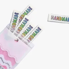 Handmade-Labels in Regenbogenfarben, teils aus der geöffneten Verpackung herausgezogen