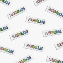 Mehrere Handmade-Labels in Regenbogenfarben locker verstreut aus unterschiedlichen Blickwinkeln