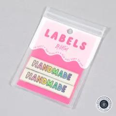 Verpackung der KATM-Labels Handmade in Regenbogenfarben mit zwei sichtbaren Endfalt-Labels, Ansicht schräg von oben