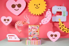 KATM Adventskalender 2026 auf Boxstapel vor rosa Kulisse mit Papierfiguren Herz, Sonne und Nähmaschine