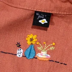 Label 'You're a Good Egg' eingenäht am Kragen eines Kleidungsstücks mit floraler Stickerei.