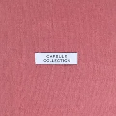 Label 'Capsule Collection' eingenäht auf altrosa Leinenstoff.