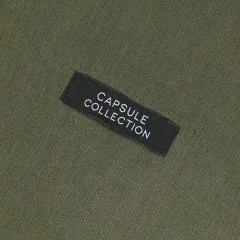 Label 'Capsule Collection' eingenäht auf olivgrünem Stoff.