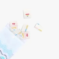 Labels quellen farbenfroh aus der geöffneten Verpackungstüte, das Herz-Label schwebt daneben.