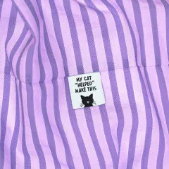 Katzengesicht-Label eingenäht in den Saum eines lila-weiß gestreiften Stoffs.