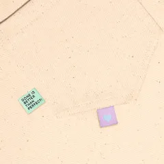 Zwei Labels eingenäht in eine cremefarbene Stofftasche mit Innensaum.