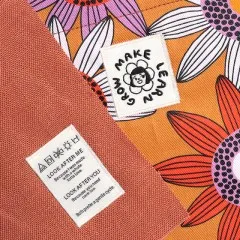 Eingenähtes Label in einer Tasche mit buntem Blumenstoff, daneben ein 'Make Learn Grow'-Patch