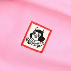 Das Label „Seam Ripper“ mit wütender Teufels-Figur ist auf rosafarbenen Stoff genäht und von einem roten Stoffrahmen eingefasst.